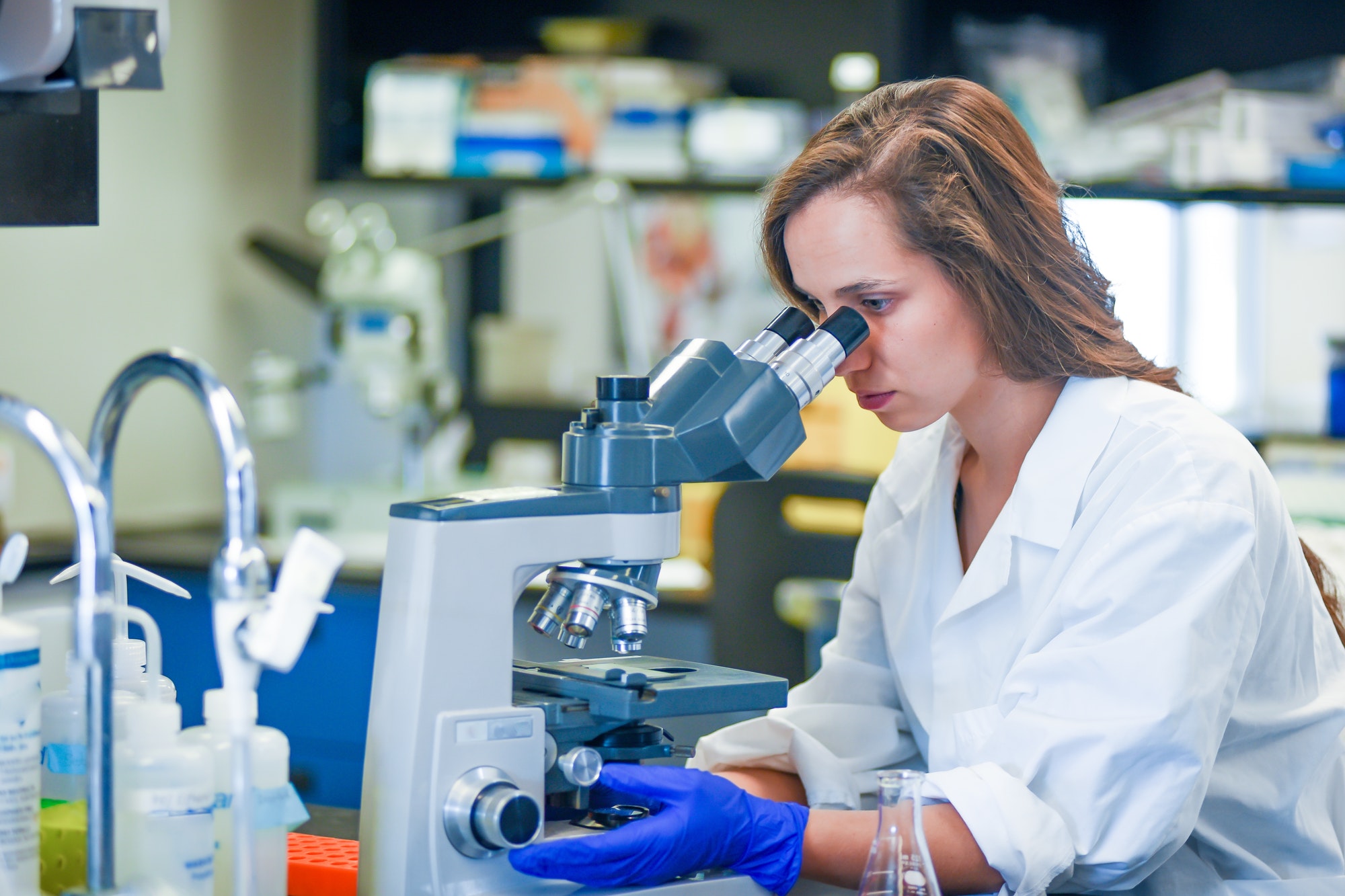 woman researcher examining sample under microscope